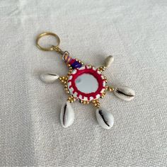 a red and white beaded keychain with feathers hanging from it's side