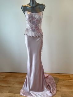 a mannequin with a dress on display in front of a white wall and wooden floor