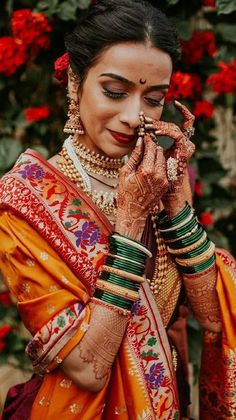 a woman in an orange sari holding her hands to her face while wearing jewelry