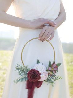 a woman wearing a white dress holding a red and white flower arrangement in her hand