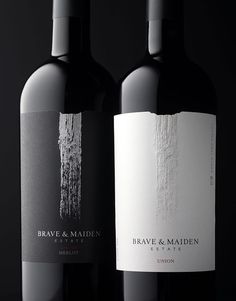 two bottles of wine sitting next to each other on a black surface with white writing