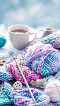 yarn and knitting needles on a table next to a cup of coffee with buttons in the background