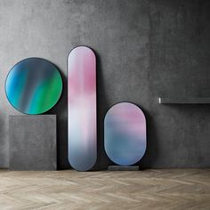 three circular mirrors on the wall next to each other in front of a concrete wall