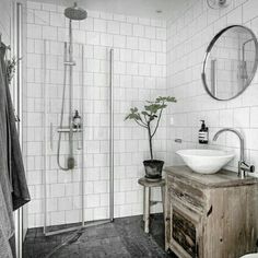 a bathroom with a sink, mirror and shower stall in black and white tile on the walls