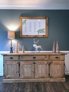 a wooden sideboard with two deer figurines and a framed poster on the wall