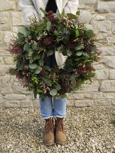 a woman holding a wreath made out of plants