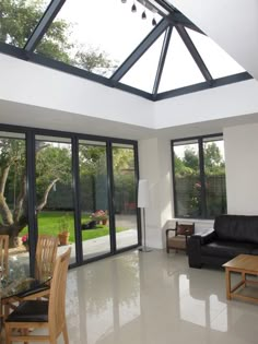 a living room filled with furniture next to a glass ceilinged dining room table and chairs