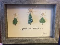 three green christmas trees in a shadow box frame with the words peace on each side