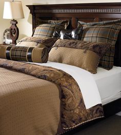 a bed with brown and tan comforters in a bedroom next to a night stand