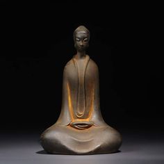 a bronze buddha statue sitting on top of a black surface in front of a dark background