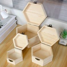 four wooden boxes sitting on top of a wood floor next to a plant and a window