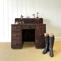 a pair of boots are sitting next to an old wooden desk with drawers on it