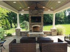 a covered patio with wicker furniture and an outdoor fireplace