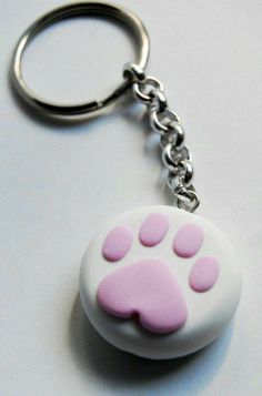 a white and pink key chain with a paw print on the front, sitting on a table