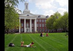 people sitting on the grass in front of a building