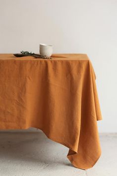 an orange linen tablecloth with a white cup on it, sitting on top of the table