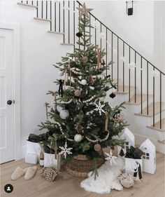 a small christmas tree in a basket next to some presents on the floor and stairs