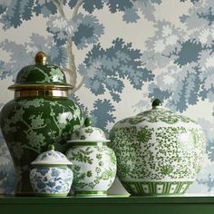 three green and white vases sitting on top of a shelf