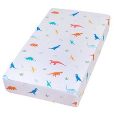 a white crib mattress with colorful dinosaurs on it