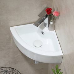 a white sink sitting on top of a wall next to a vase with flowers in it