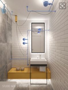 a bathroom with white brick walls and blue piping on the ceiling above the sink