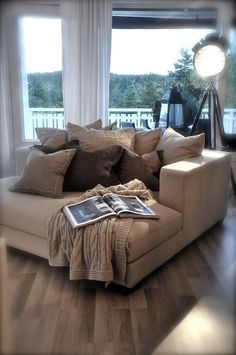 a living room filled with lots of furniture and pillows on top of a hard wood floor