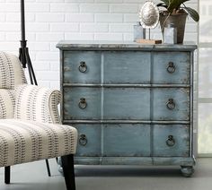 a blue dresser sitting next to a white chair