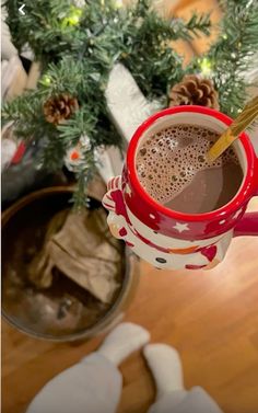 a cup of hot chocolate sitting on top of a table next to a christmas tree