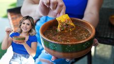 a woman is holding a bowl of chili