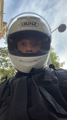 a person wearing a helmet and jacket with trees in the background