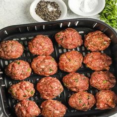 meatballs are being cooked in an air fryer with spices and seasonings on the side