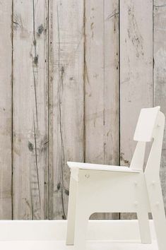 a white chair sitting in front of a wooden wall