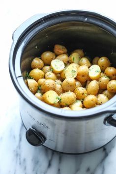 a crock pot filled with potatoes and parsley