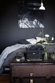 a bedroom with a typewriter and flowers on the table in front of the bed