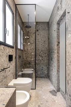 a bathroom with three toilets and two sinks in it's center wall, surrounded by stone walls