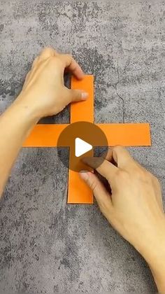 someone is cutting out an orange piece of paper with scissors and tape on the floor