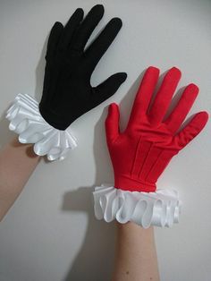 two hands wearing red and black gloves with white ruffles