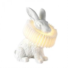 a white rabbit figurine with a yellow light around its neck and ears, on a white background