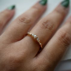 a woman's hand with green nail polish and gold ring