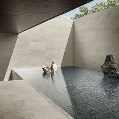 a rock sits in the middle of a small pool next to a large stone boulder