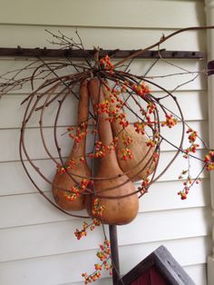 two gourds are hanging from the side of a house with berries on them