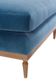 an upholstered blue couch with wooden legs