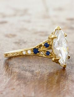 an antique diamond and blue sapphire ring on a wooden surface with gold trimmings