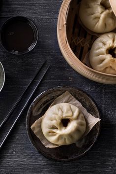 some dumplings are sitting on a table with chopsticks next to them and two bowls