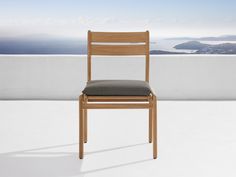 a wooden chair sitting on top of a white floor next to a wall and ocean