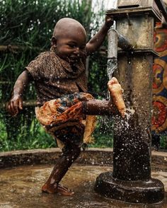 a young boy is playing in the water from a sprinkler on his feet