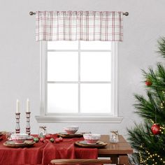 a dining room table set for christmas with red cloths and place settings on it