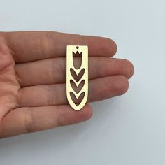 a hand holding a gold colored metal object with an arrow on it's side