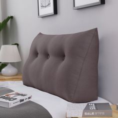 a gray pillow sitting on top of a bed next to two pictures and a lamp