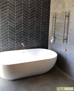 a white bath tub sitting next to a tiled wall